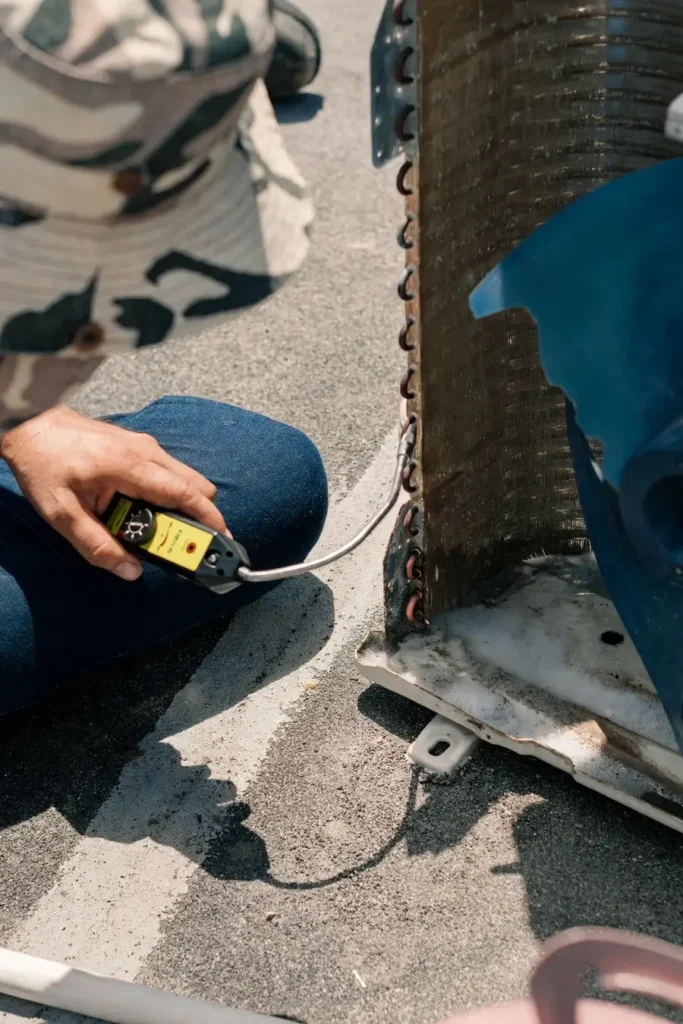Close-up of a technician checking an air conditioner coil for refrigerant leaks with an electronic leak detector