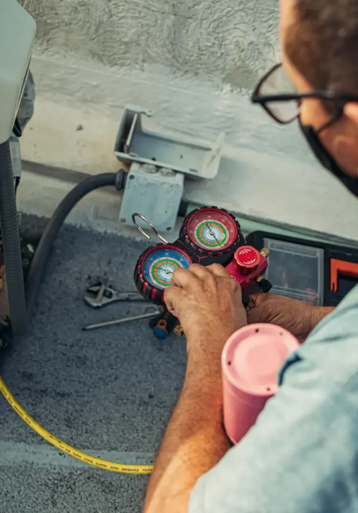 Technician reading a manifold gauge set while servicing an air conditioning system