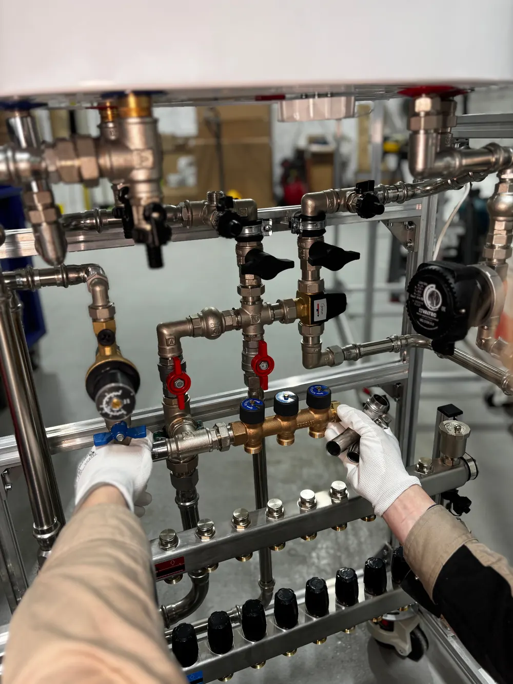 New valves and manifold pipework fitted beneath a wall-mounted boiler during installation