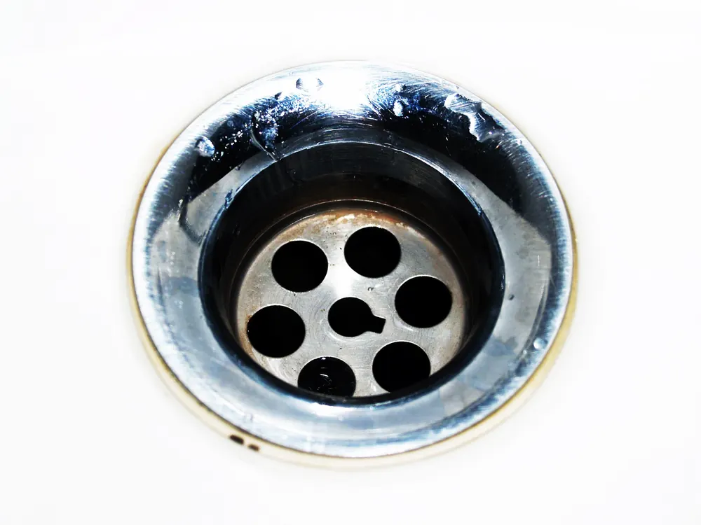 Close-up of a metal sink drain strainer, where most household drain clogs start