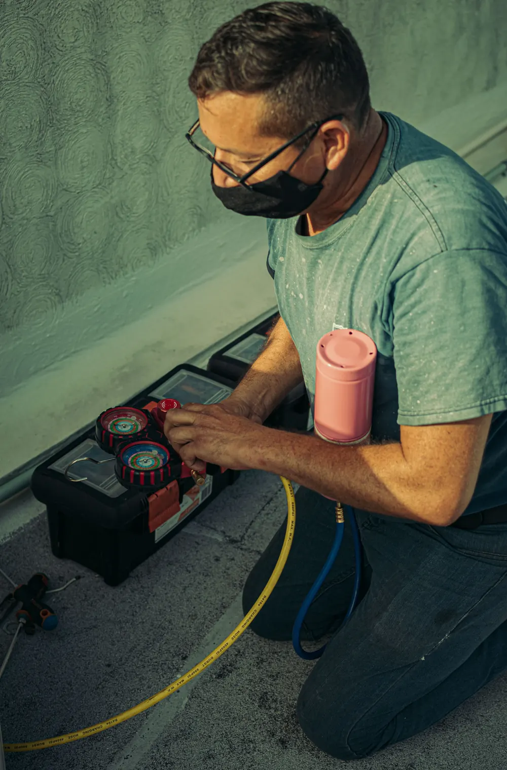 Technician kneeling with gauges and tools while servicing a home heating unit