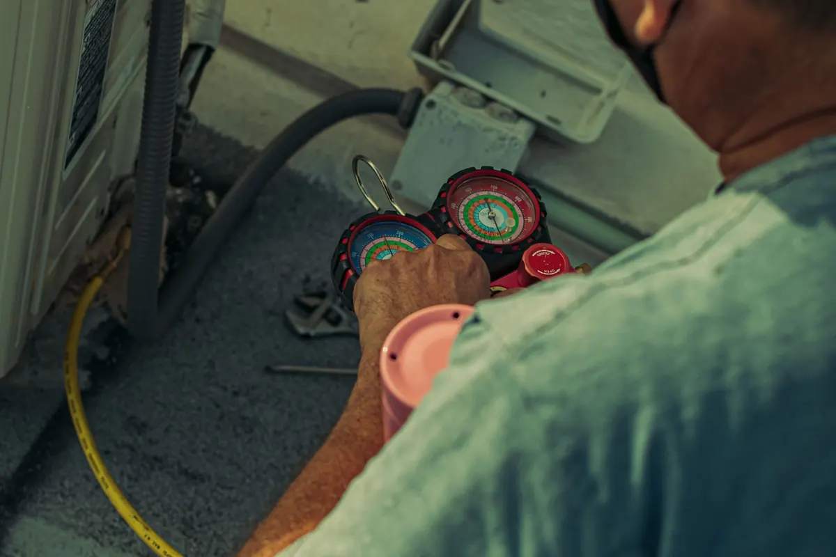 HVAC technician testing a home heating system with a manifold gauge set during a furnace repair visit