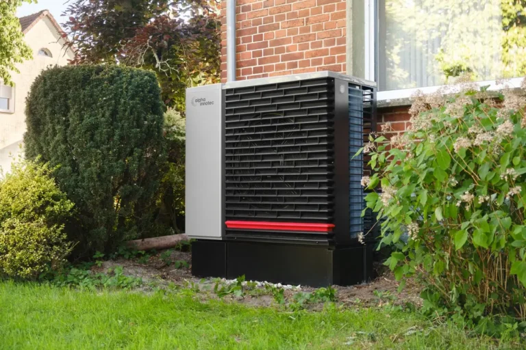 Modern air-source heat pump installed in a garden beside a brick home