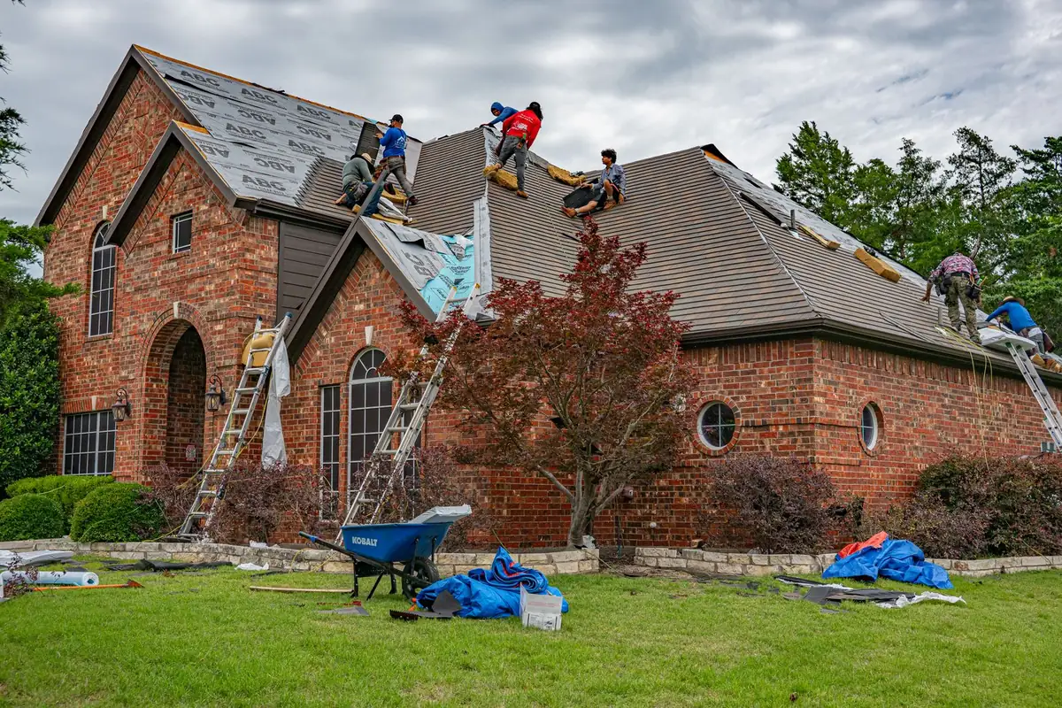 Roofing crew installing shingles and underlayment on a brick home