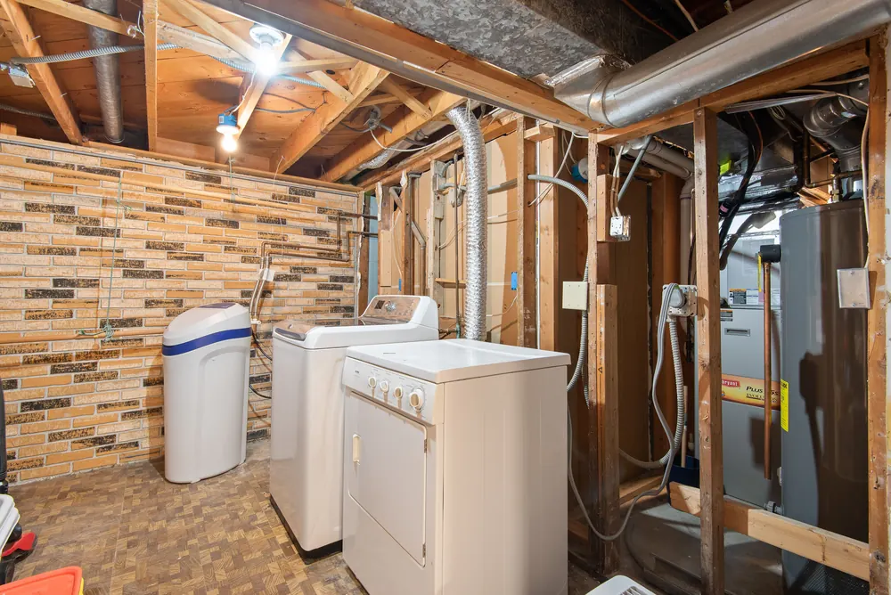 Basement utility area with a conventional tank water heater and furnace, the bulky setup a wall-mounted tankless unit replaces