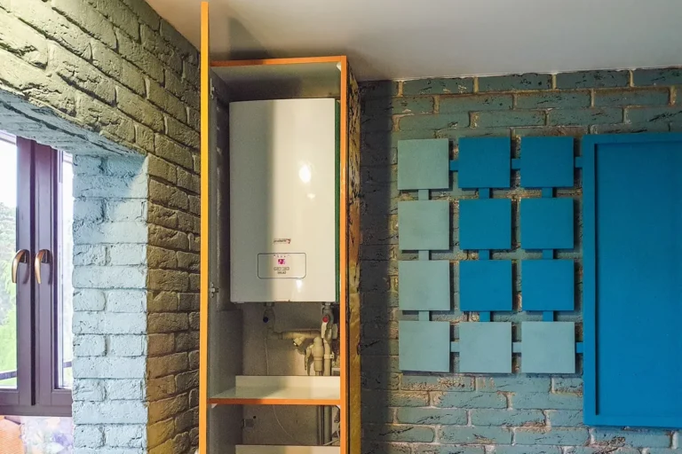 Compact wall-mounted tankless water heater installed inside a cabinet niche, showing its digital temperature display